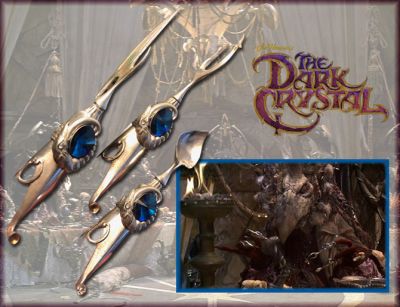 Skeksis Cutlery
A set of Skeksis finger cutlery from Frank Oz and Jim Hensonâ€™s fantasy film The Dark Crystal. These eating utensils were used in the banquet scene as the lizard-like Skeksis creatures ate a massive dinner and discussed the escape of Jen (performed by Jim Henson and voiced by Stephen Garlick). Made of metal with blue colored crystals and faux diamonds, the cutlery resembles a knife, a skewer and a spoon and is designed to be worn like finger rings. The utensils feature ornate detailing with rings of runes around their circumference and the mouth of a Skeksis wrapped around the colored gem at the fingertip.
Keywords: Skeksis Cutlery